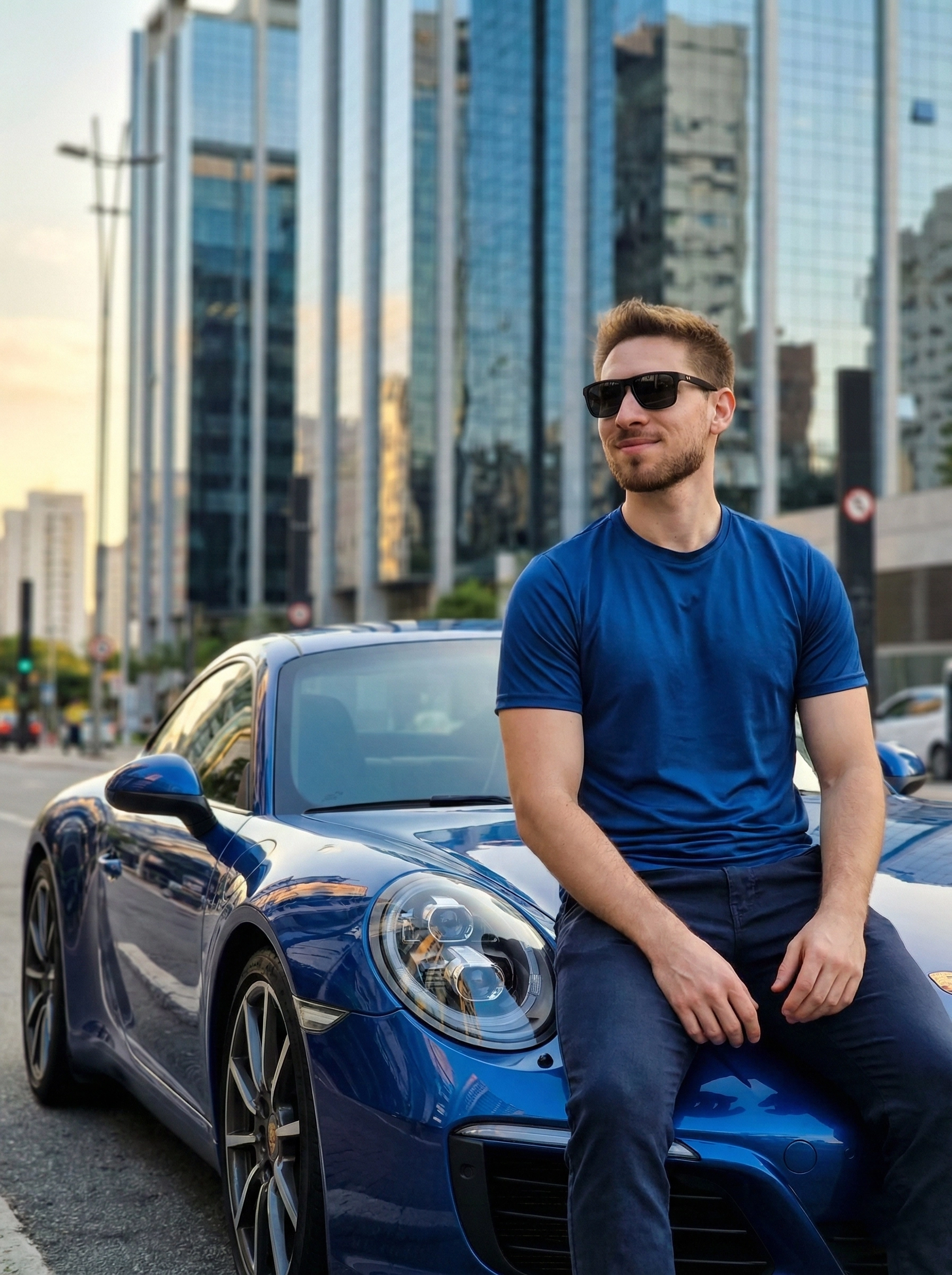 Стильный человек на капоте синего Porsche в городской среде