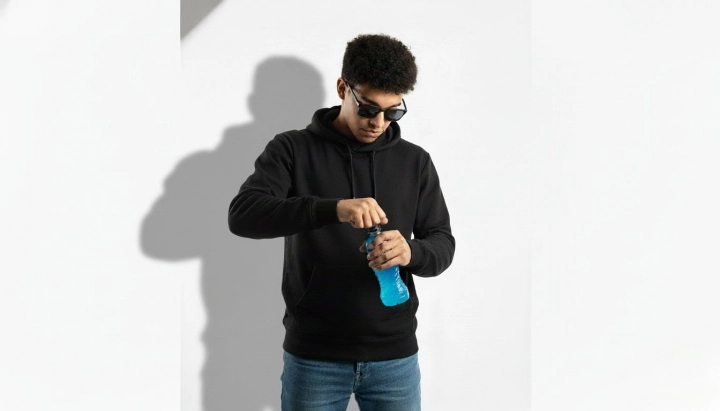 Мужчина открывает синюю бутылку Powerade